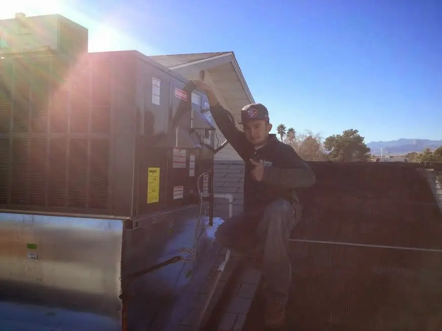 HVAC technician performing AC Tune-Up on a rooftop unit in Delano