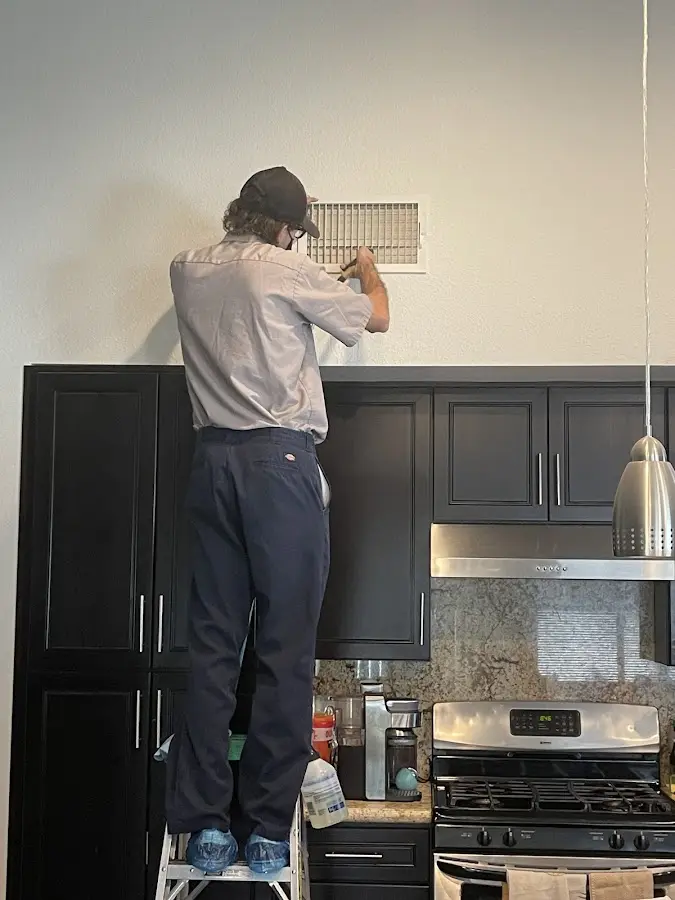 Technician inspecting an air vent during HVAC service in Delano